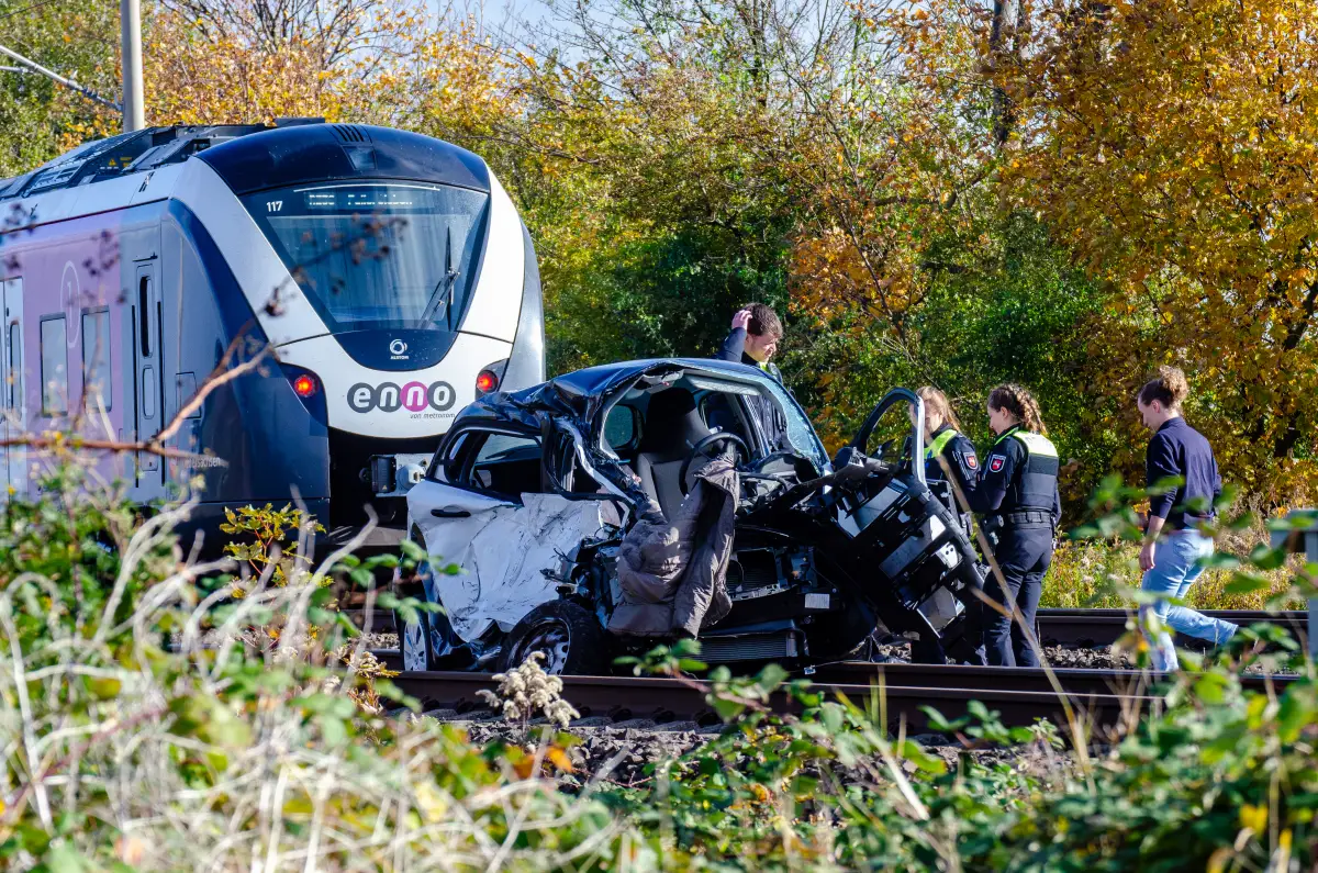 Einsatzkräfte stehen an dem Fahrzeug nach dem Unfall auf dem Bahnübergang.